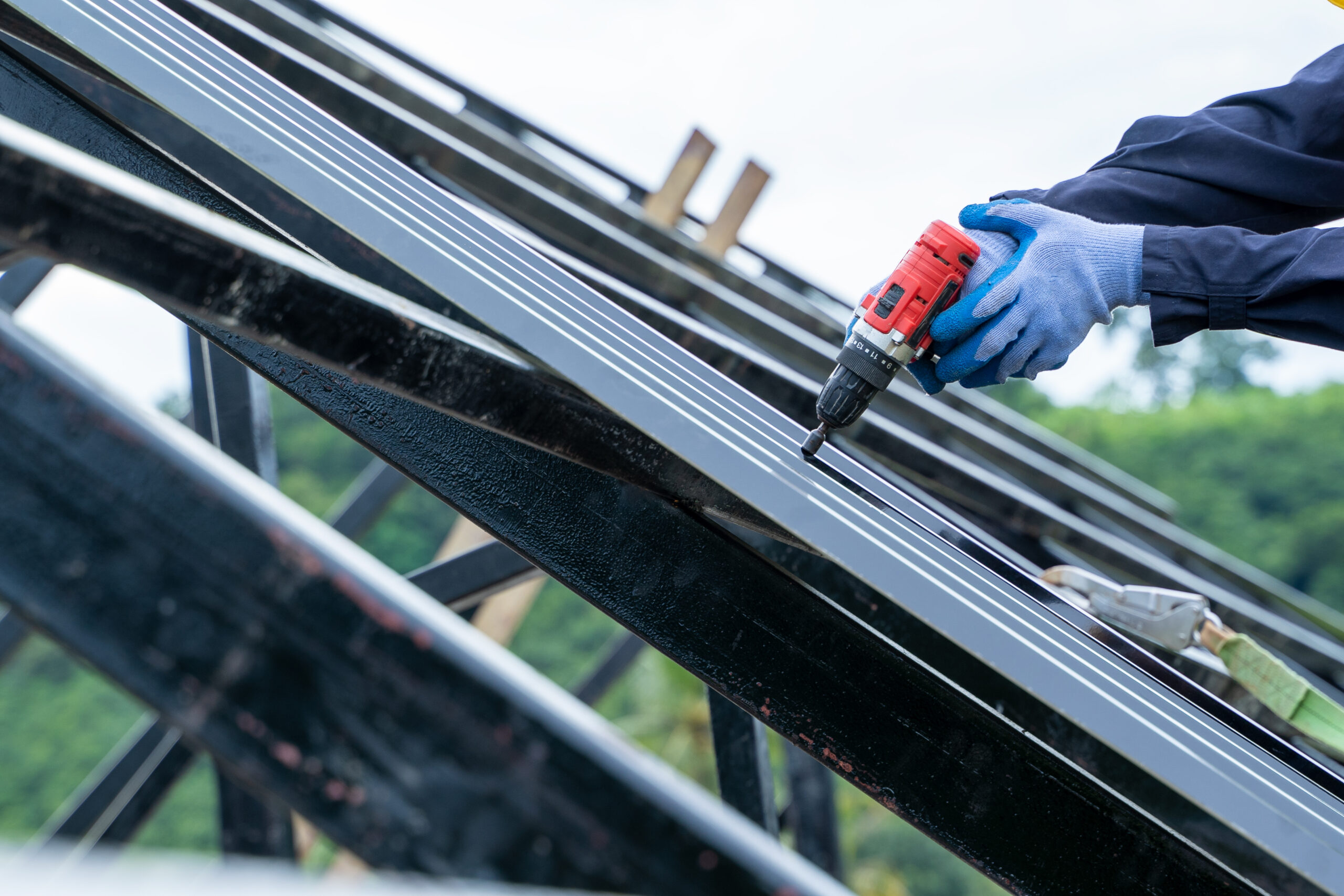 Roofer in protective gear using pneumatic tools, highlighting emergency roofing services northeast Florida.