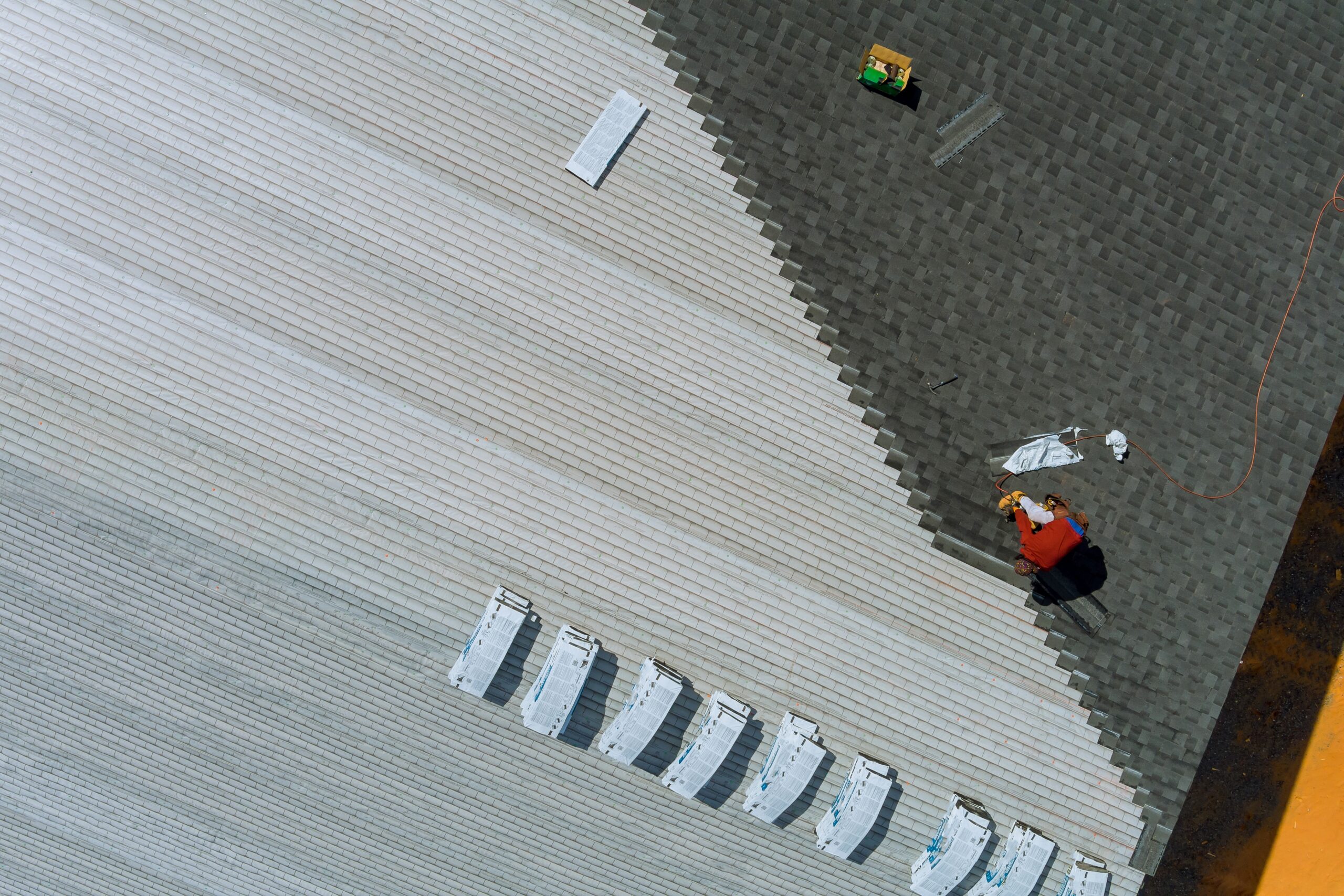 emergency roofing services northeast florida - Aerial view of roof installation with workers laying asphalt shingles, showcas