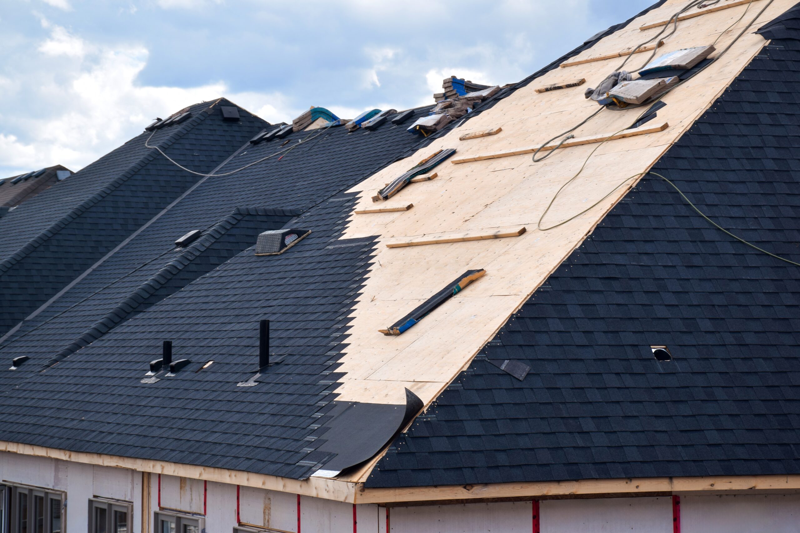 Closeup of black roof shingles being installed on a new residential home, highlighting roofing services Jacksonville FL.